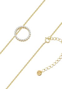 Guldhalsband med en cirkulär hänge prydd med klara ädelstenar. Kedjan har ett justerbart spänne med en logotags.