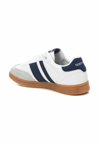 Sneaker bianco con strisce blu navy, punta in suede e suola in gomma. Presenta il logo "TEDDY'S" sul retro e chiusura con lacci.