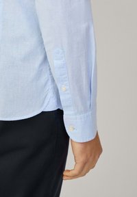 Lichtblau gestreepte blouse met kraag en lange mouwen, voorzien van knoopmanchetten en een gladde stoftextuur.
