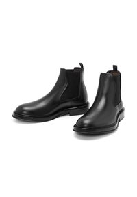 Bottes Chelsea en cuir noir avec panneaux élastiques sur les côt és et languettes de traction, finition lisse et semelle plate en caoutchouc.