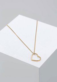 Guldtonet metal halskæde med vedhæng i hjerteform, på en delikat kæde, med en glat finish og minimalistisk design.