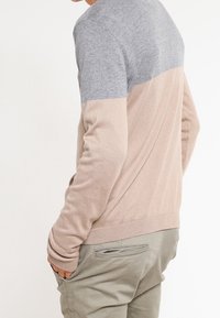 Pull en tricot avec une partie supérieure grise et une partie inférieure beige, des poignets et un ourlet côtelés. Coupe slim avec une texture lisse.