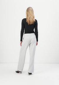 Pantalons larges gris avec une coupe ajustée, taille élastique et poches latérales, associés à un haut noir ajusté à manches longues.