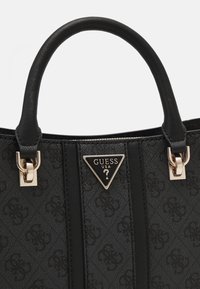 Sort håndtaske med tekstureret materiale, med en trekantet logo med gulddetaljer og læderhåndtag. Mønstret overflade med vandrette linjer.