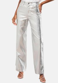 Srebrne, hlače visokega pasu s teksturo krokodila; širok rez; kovinski zaključek; v kombinaciji z zlatimi sandalčki na vezalko.