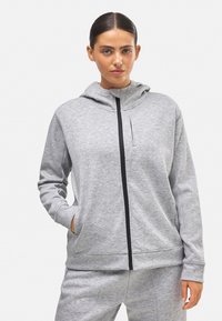 Sudadera gris con cremallera, hecha de material suave, que cuenta con un bolsillo frontal, un cuello alto y detalles en cremallera negra. Textura suave en toda la prenda.