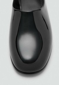 Černá laková kůže s hladkým, zaobleným špičkou a mírným leskem. Minimalistický design s čistou siluetou a bez viditelných ozdob.