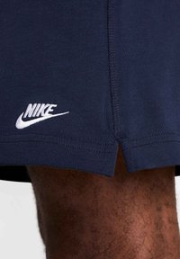 Pantalones cortos deportivos en color navy con un dobladillo dividido, con un logo blanco de Nike en el lado izquierdo. Fabricados con una tela suave y ligera.