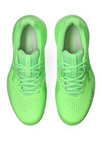 Die grünen Sportschuhe haben eine glatte Textur, Mesh-Einsätze, perforierte Details und flache Schnürsenkel, die für Komfort und Leistung ausgelegt sind.