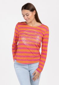 Langärmliges T-Shirt mit kräftigen orange- und pinkfarbenen Streifen, rundem Halsausschnitt und einem glitzernden Grafikdruck in der Mitte. Weicher Stoff.