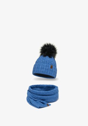 Blauwe gebreide beanie met een zwarte bontpompon en een bijpassende blauwe gebreide sjaal. De stof heeft een gemêleerd patroon met een label op de beanie.