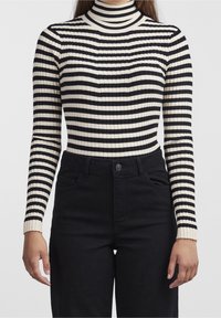 Czarny i kremowy pasek prążkowany golf z długimi rękawami, dopasowany fason i teksturowana tkanina. Połączony z czarnymi jeansami z wysokim stanem.