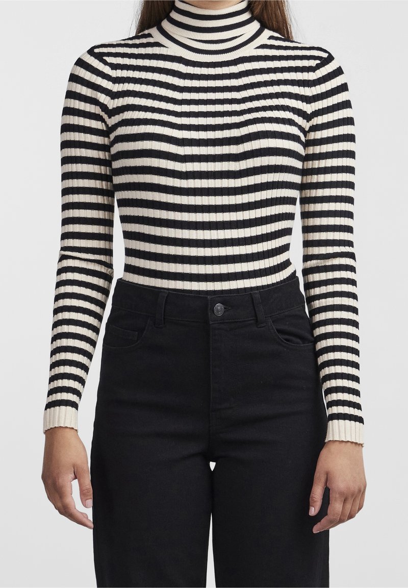 Czarny i kremowy pasek prążkowany golf z długimi rękawami, dopasowany fason i teksturowana tkanina. Połączony z czarnymi jeansami z wysokim stanem.