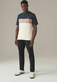 Herre farveblokket t-shirt har en marineblå top, en pink vandret stribe og en hvid bund. Lavet af en bomuldsblanding, med korte ærmer og rund hals.