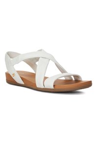 White leather sandals with crisscross strap design, brown sole, and textured accents. Features a flat heel for comfort and easy wear.
