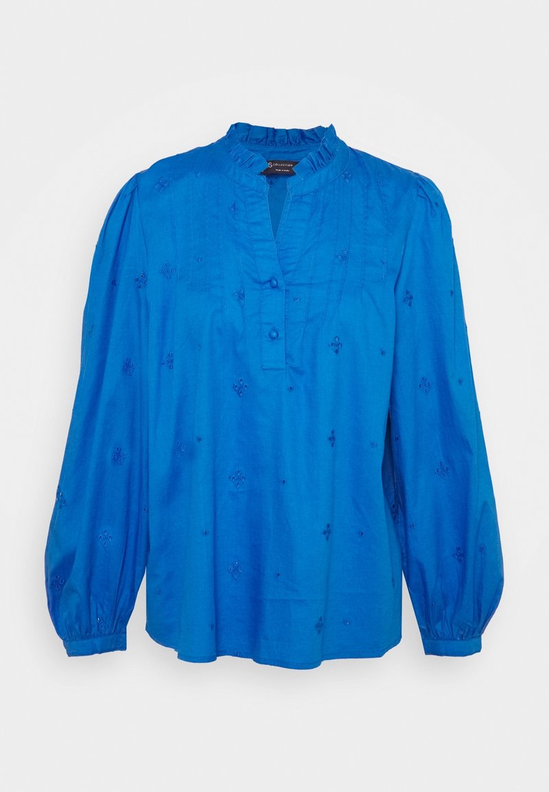 Blusa di cotone blu con colletto arricciato, chiusura con bottoni e maniche lunghe a sbuffo. Presenta sottili dettagli ricamati in tutto il capo.