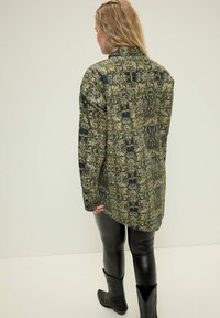 Camicia a maniche lunghe con stampa a serpente in tonalità di verde, nero e oro. Realizzata in tessuto morbido, ha una vestibilità comoda.