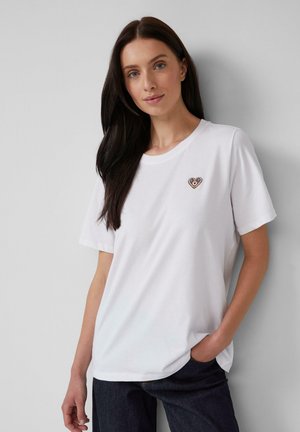 T-shirt en coton blanc à manches courtes et col rond, avec un petit cœur brodé sur la poitrine gauche.