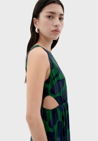 Abito senza maniche in verde e blu navy con motivi astratti, caratterizzato da fianchi aperti e una gonna fluida e arricciata. Tessuto liscio.