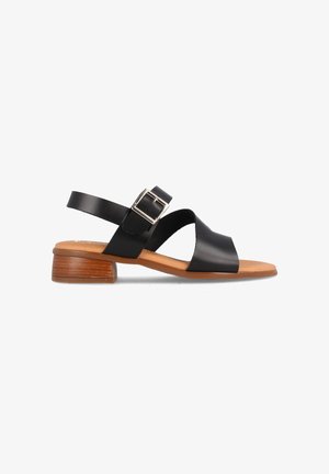 Sandalias de cuero negro con tacón plano, con un diseño entrecruzado y correa ajustable con hebilla. La suela es de un material color marrón claro que imita la madera.