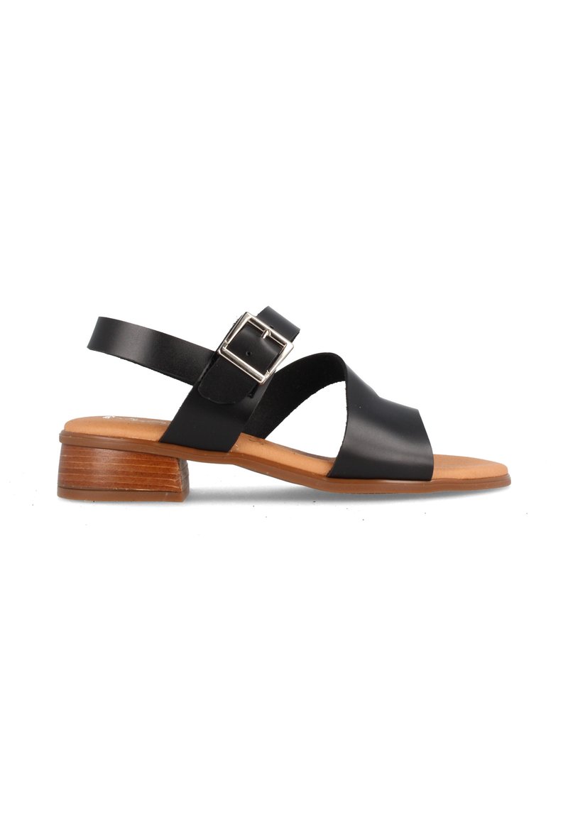 Sandalias de cuero negro con tacón plano, con un diseño entrecruzado y correa ajustable con hebilla. La suela es de un material color marrón claro que imita la madera.
