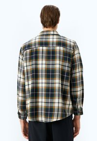 Geruite flanellen shirt in roomwit, groen, marineblauw en oranje. Heeft lange mouwen, een kraag en knoopmanchetten met een relaxte pasvorm.