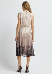 Vestido fluido en degradado de beige a marrón oscuro, con rayas verticales y una cintura ajustada. Presenta una espalda con botones y un diseño sin mangas.