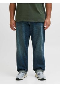 Blauwe spijkerbroek met een relaxte pasvorm, vervaagde afwerking, rechte pijpen en een opgerolde zoom, gecombineerd met grijze sportschoenen.