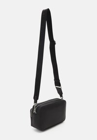 Borsa a tracolla rettangolare nera con esterno in pelle liscia, chiusura con zip e tracolla in tessuto strutturato con marchio.