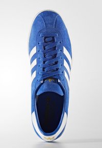 Blå mockasinsneaker med vita ränder, rundad tå, snörning, vadderad plös och guldfärgad logotypdetalj på innersulan.