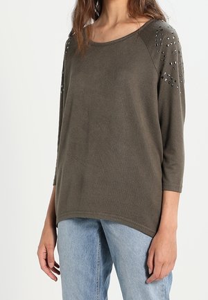 Olivgrüner Pullover mit Dreiviertelärmeln, der mit Nietenakzenten an den Schultern und einem lockeren Schnitt gestaltet ist, gefertigt aus weichem, strukturiertem Material.