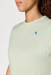 Svijetlozelena majica s kratkim rukavima i okruglim izrezom, s izvezenim logotipom u tamnoplavoj boji i glatkom, mekanom teksturom.