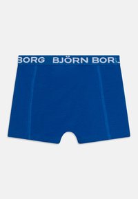 Blå boksershorts laget av mykt stoff med en hvit logo-linning. Funksjoner inkluderer en tettsittende design og glatte sømmer.