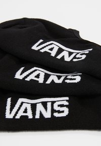 Calcetines de algodón negros con el logotipo "VANS" tejido en blanco. Textura suave, parte superior acanalada y sin patrones visibles ni acentos adicionales.