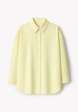 Lichtgele blouse met lange mouwen, knoopsluiting, klassieke kraag en met knopen afgesloten manchetten, getoond tegen een witte achtergrond.
