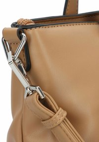Leren handtas in een tan kleur met een gladde textuur, voorzien van zilveren hardware en een gevlochten detail aan de rand van de opening.