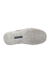 Semelle de chaussure avec une surface en caoutchouc texturée, présentant un motif de crampons unique. La couleur est gris clair avec une étiquette de marque noire.