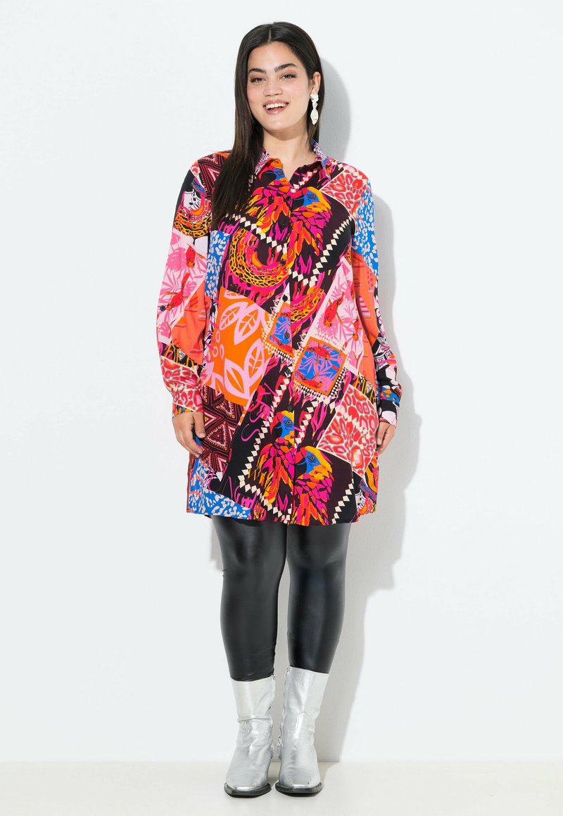 Abito camicia colorato e con fantasia, a maniche lunghe, con disegni geometrici e floreali in rosso, rosa, blu e nero. Abbinato a leggings neri e stivali argentati.