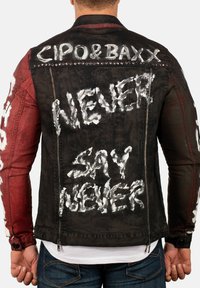 Veste en denim noire et rouge à manches longues ; arbore un texte graffiti blanc "NEVER SAY NEVER" et un logo au dos ; fermeture éclair.