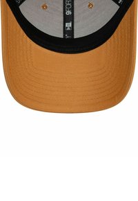 Beige Kappe mit schwarzem Rand, aus strukturiertem Stoff, mit gebogenem Schirm und belüfteten Ösen entlang des inneren Bands.
