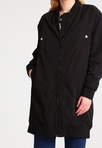 Czarna pikowana kurtka z zamkiem błyskawicznym z przodu, ściągaczami przy mankietach oraz dwoma przednimi kieszeniami z zatrzaskami. Gładka tekstura, do kolan.