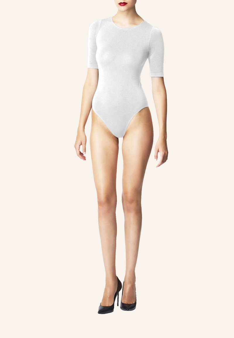 Vit bodysuit med korta ärmar, slät textur, högskurna benöppningar. Bärs med svarta högklackade skor, minimalistisk design.