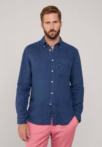 Donkerblauwe overhemd met lange mouwen en knoopsluiting, voorzien van een borstzak, gemaakt van lichte stof. Het heeft een licht gestructureerde afwerking en witte knopen.
