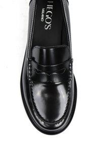 Czarne skórzane mokasyny o błyszczącym wykończeniu, z plecionymi akcentami na cholewce, okrągłym noskiem i kontrastowym przeszyciem wzdłuż podeszwy.