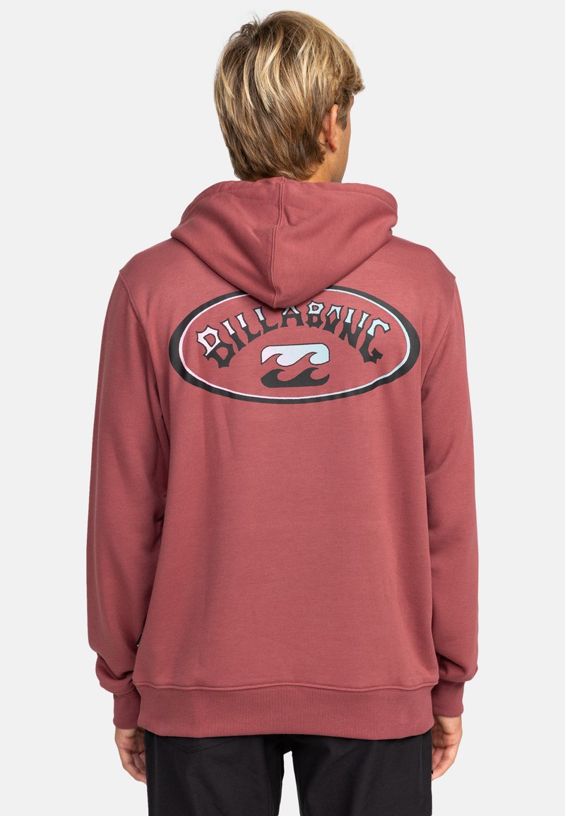 Sudadera color burdeos hecha de tela suave, con un gran logo circular en la parte posterior que presenta el texto "Billabong" y un diseño de ola en colores contrastantes.