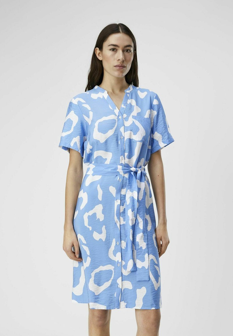 Blaues Hemdblusenkleid mit weißem Leopardenmuster, kurzen Ärmeln, V-Ausschnitt und einem Bindegürtel. Glatte Textur und knielanges Design.