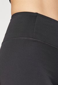 Leggings neri a vita alta realizzati in materiale liscio ed elastico, dotati di cuciture piatte e una cintura senza cuciture per garantire comfort.