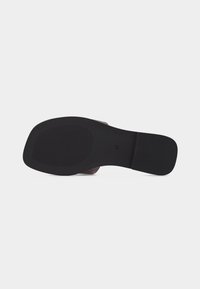 Semelle d'une sandale plate noire montrant une surface antidérapante texturée au niveau des orteils et du talon, avec la taille 37 estampillée près de la voûte plantaire.
