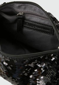 Schwarze Pouch mit Pailletten und glänzender Oberfläche. Das Innenfutter hat eine graue Beschichtung und eine Reißverschlusstasche. Ein Lederetikett ist an der Oberseite sichtbar.