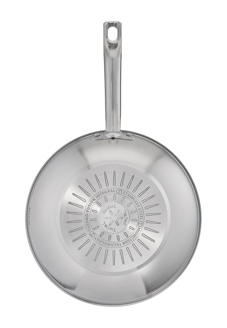 Poêle en acier inoxydable avec une surface lisse et brillante, un fond plat et une longue poignée. Présente un fond texturé avec des marquages gravés.